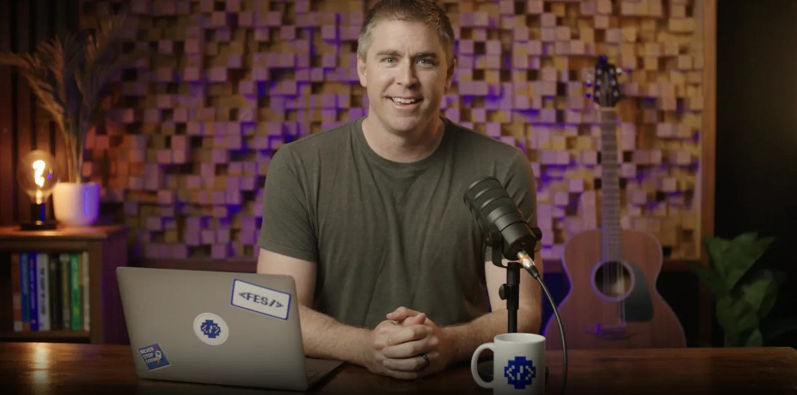 Eric Presnall presenting on camera for FES Institute, with the client's branding on the laptop and mug, lit set and broadcast microphone